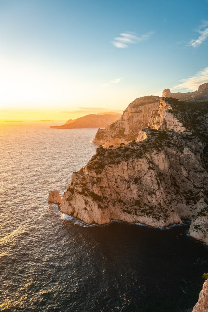 Sunset over rugged cliffs and rocky coastline with deep blue sea and warm glowing sky wallpaper