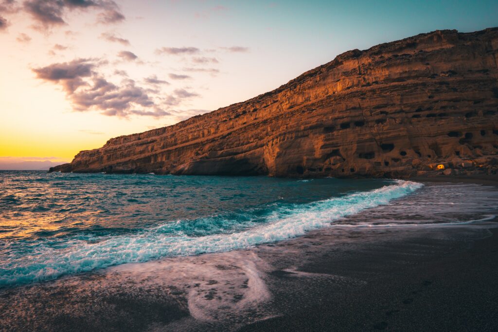 Coastal sunset wallpaper with rugged cliffs golden light and gentle waves on colorful sky background