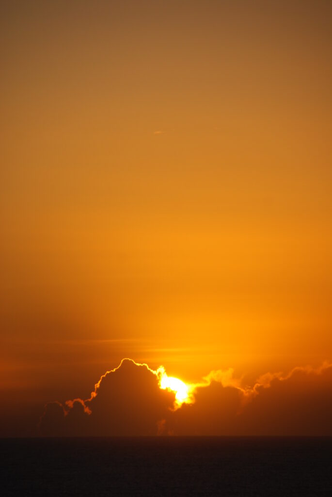 Sunset wallpaper showing golden sun dipping below horizon with warm orange glowing clouds