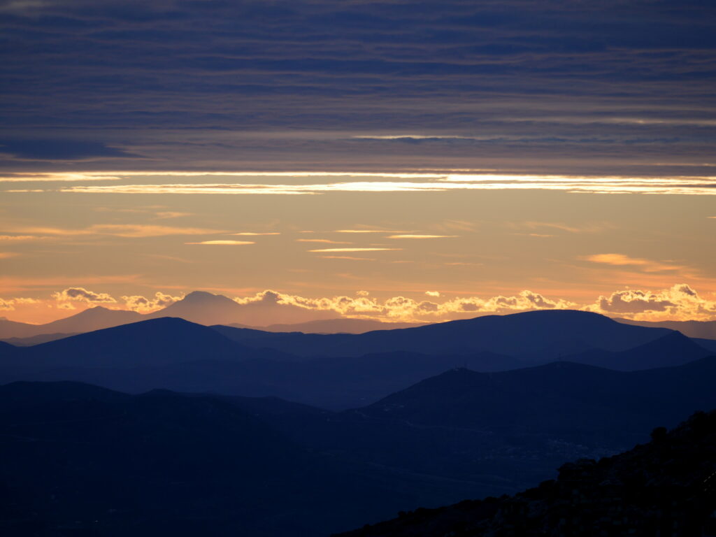 Mountain landscape at sunset with glowing sky and soft silhouettes of rolling peaks wallpaper background