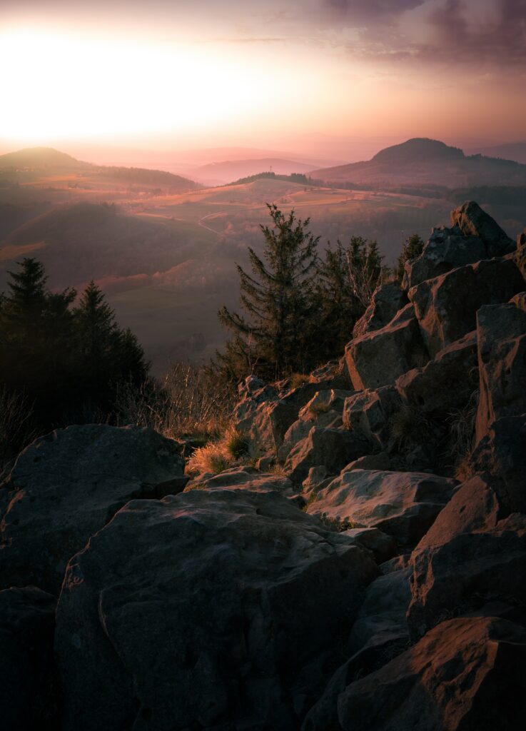 Sunset over rugged mountain rocks with misty fog and warm golden sunlight scenic wallpaper