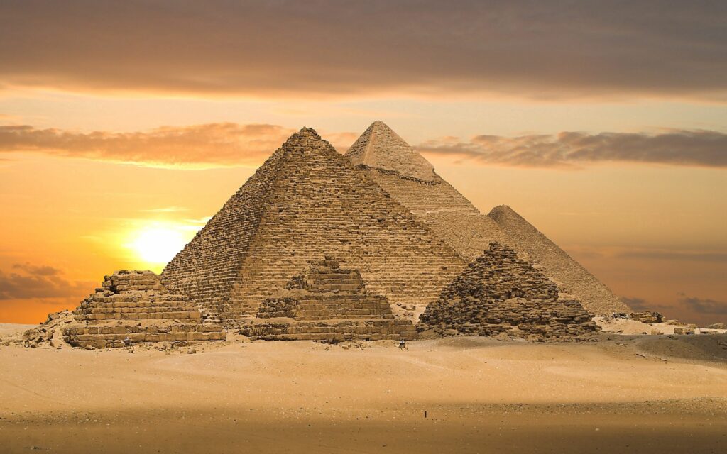 Ancient Egyptian pyramids at sunset in golden desert landscape timeless architectural wonders wallpaper