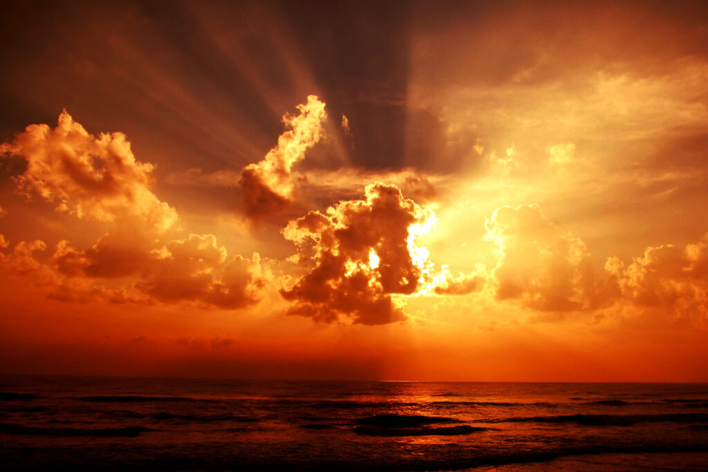 Breathtaking sunset over calm sea with golden clouds glowing vibrant orange and gold hues Wallpaper