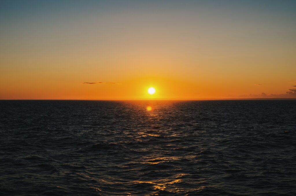 Sunset over calm sea with golden orange hues and gentle ripples reflecting soft sunlight wallpaper