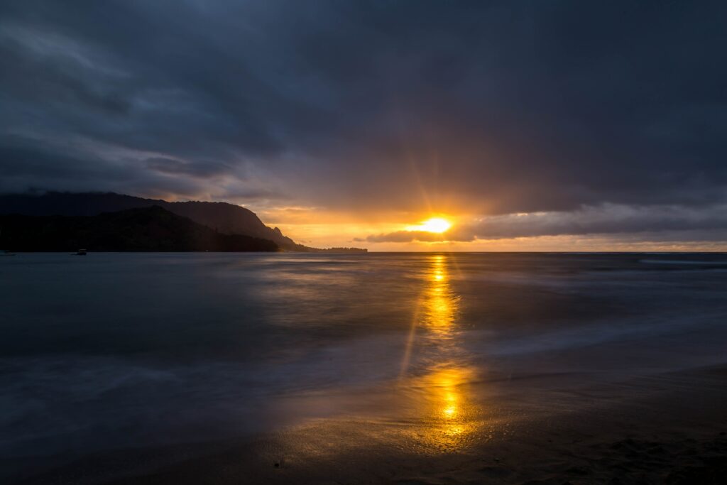 Breathtaking sunset over calm sea waves with golden sunlight and soft clouds on horizon wallpaper