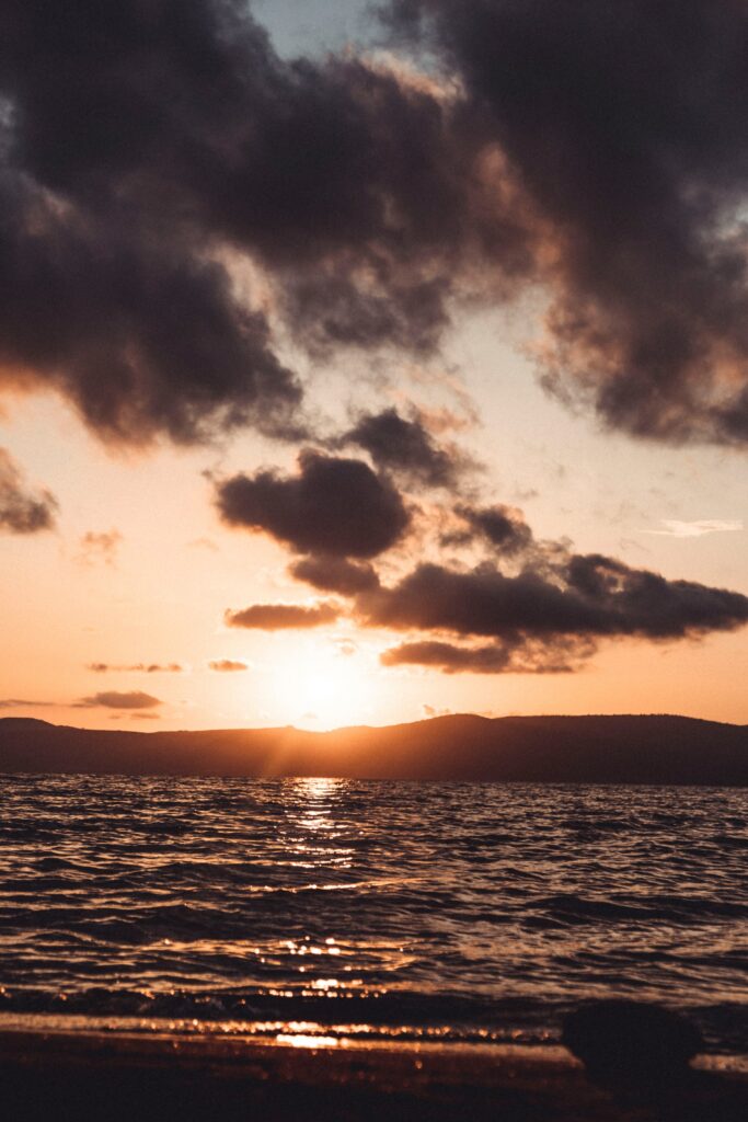 Breathtaking sunset wallpaper with golden glare over rippling water and dramatic clouds horizon