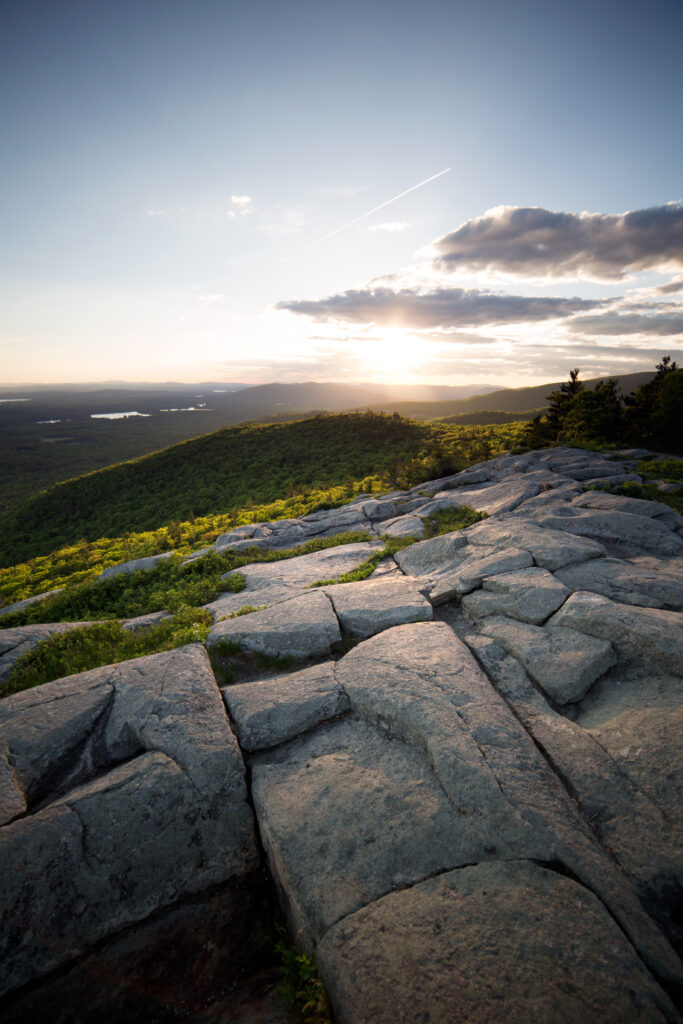 Rugged stone slabs lead to green hills under golden sunset sky serene nature wallpaper background