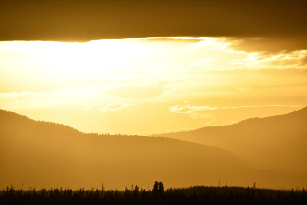 Golden sunset over rolling hills and grassy landscapes with warm yellow and orange tones wallpaper