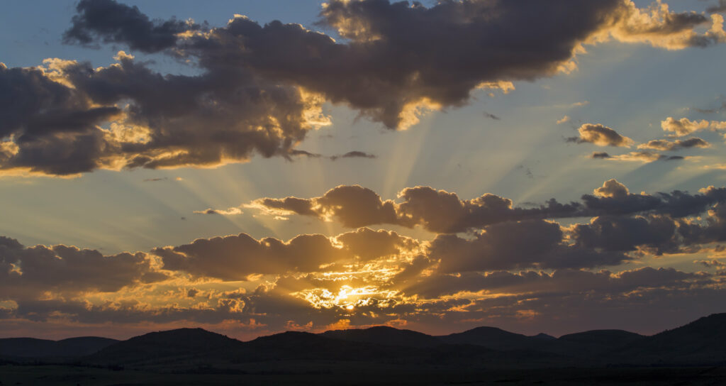 Golden sunset over rolling hills with vibrant orange yellow and purple clouds peaceful sky Wallpaper