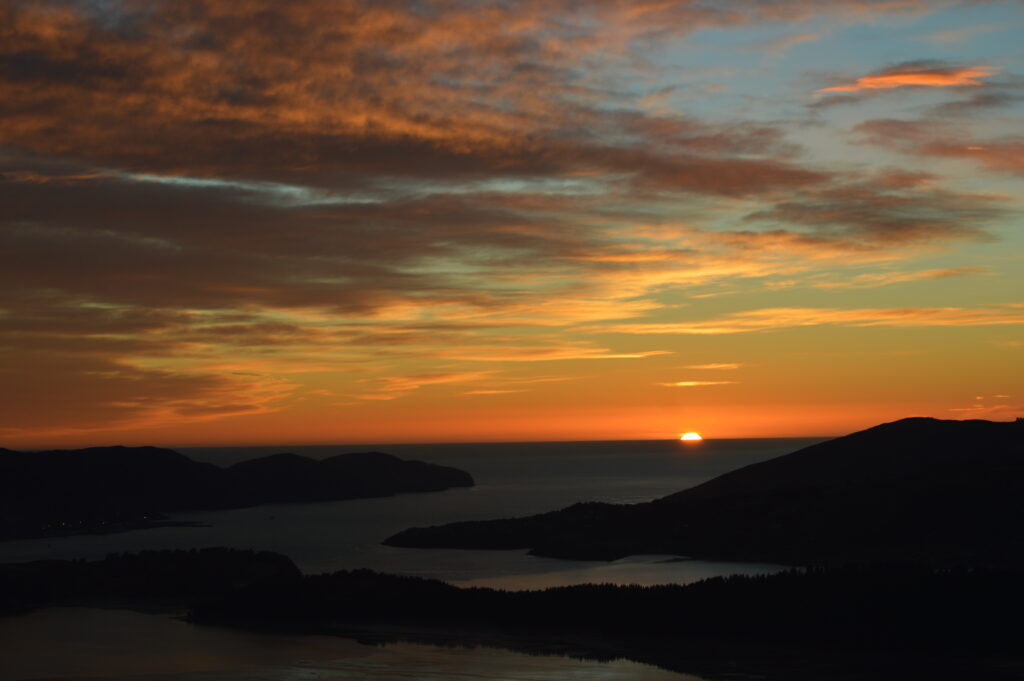 Sunset over rugged coastline with golden hues reflecting on calm sea peaceful dusk wallpaper