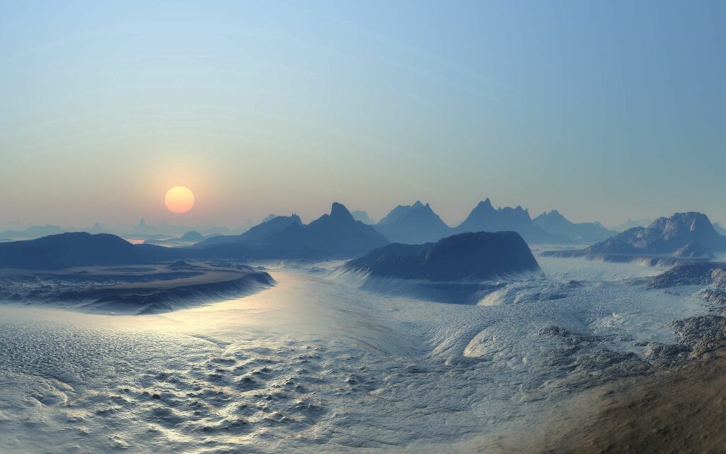 Sunset over rugged mountains with golden light on icy textured terrain and clear blue sky Wallpaper