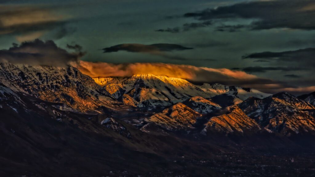 Sunset over rugged snowy mountain peaks with dramatic clouds and vivid colorful sky wallpaper