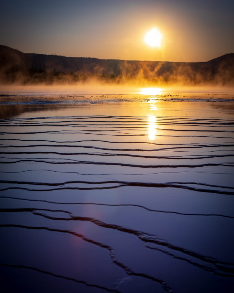 Serene lake at golden sunset with calm water foggy atmosphere and shimmering ripples wallpaper