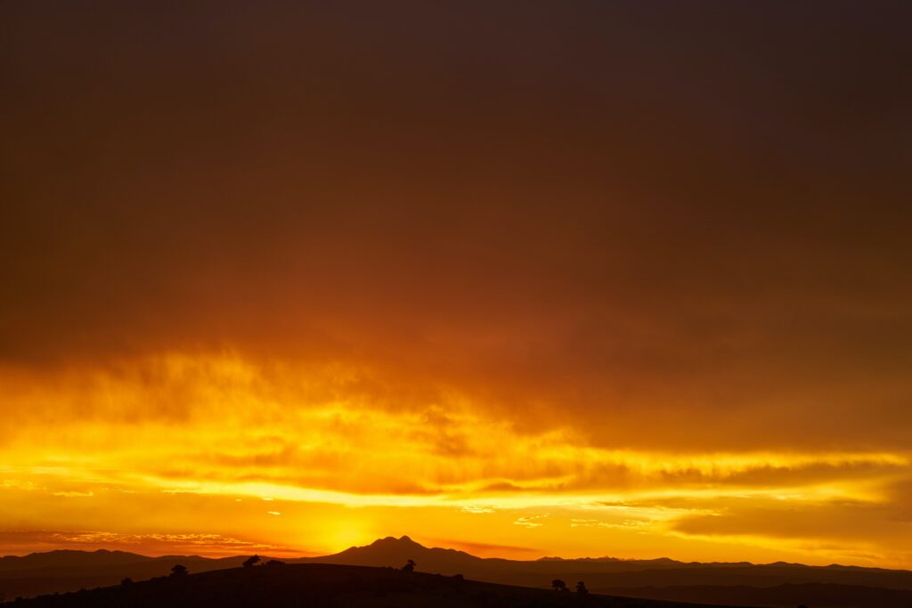 Sunset wallpaper with rolling hills silhouette and warm orange golden sky for serene landscape