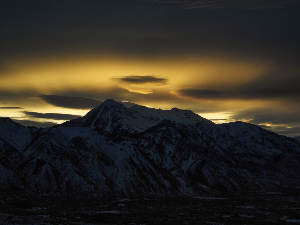 Snowy mountain peaks silhouetted at sunset with golden amber sky dramatic serene landscape wallpaper