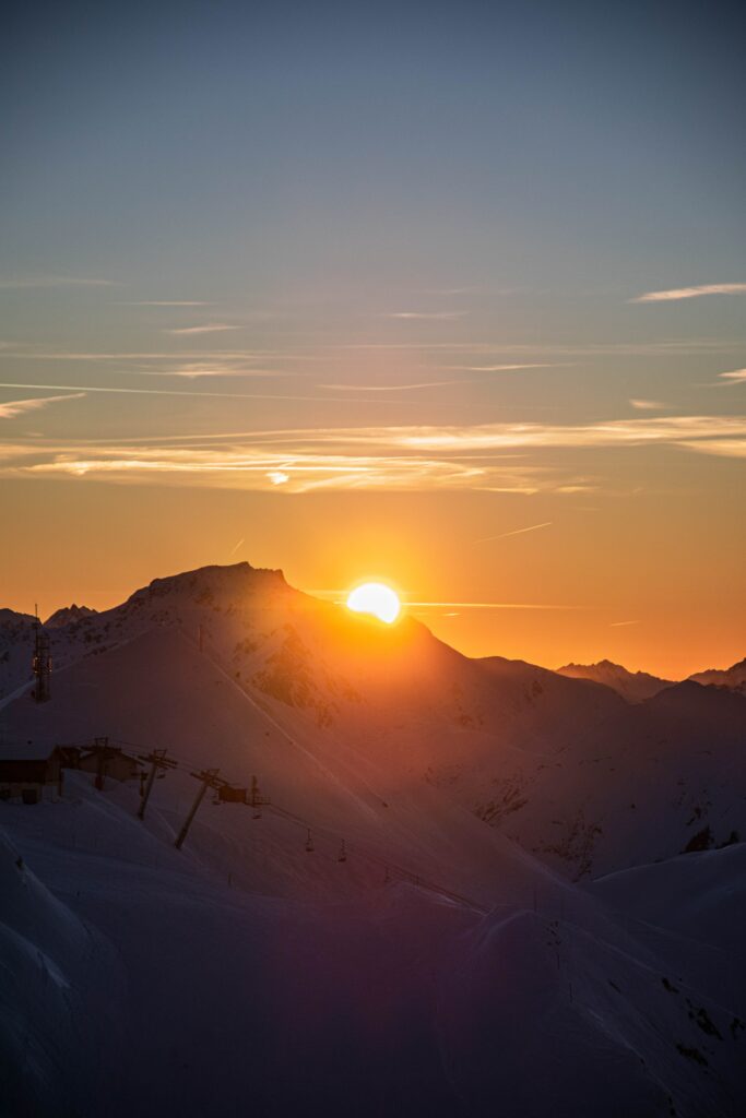 Golden sunset over snow-covered jagged mountain peaks with pastel sky and tranquil landscape Wallpaper
