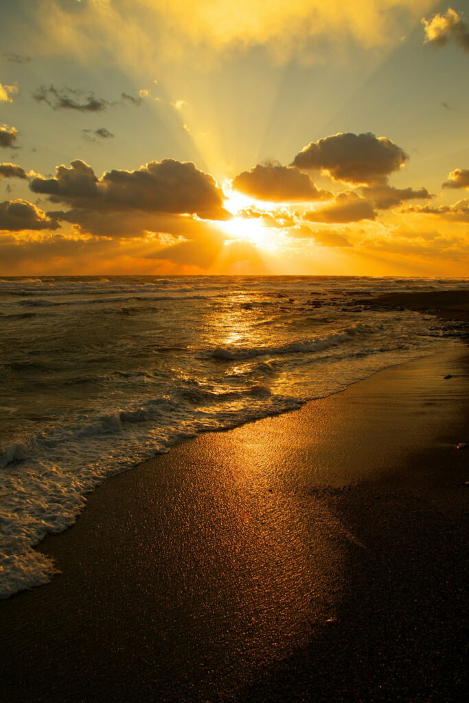 Sunset wallpaper with golden sun setting over shimmering sea and warm coastal waves at dusk