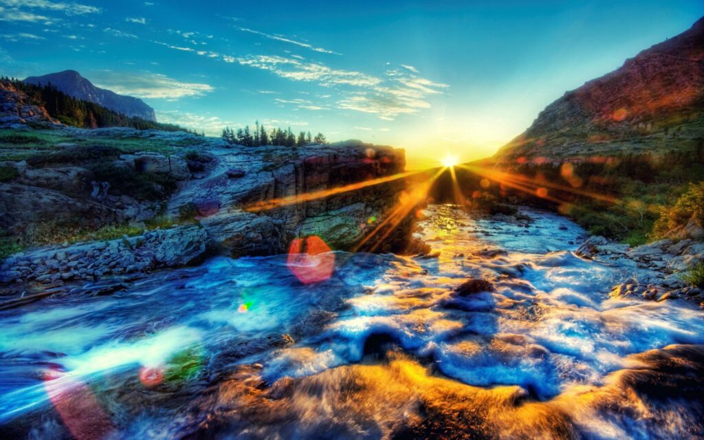 Vibrant wallpaper of rushing river with foamy water glowing under golden sunset sky landscape
