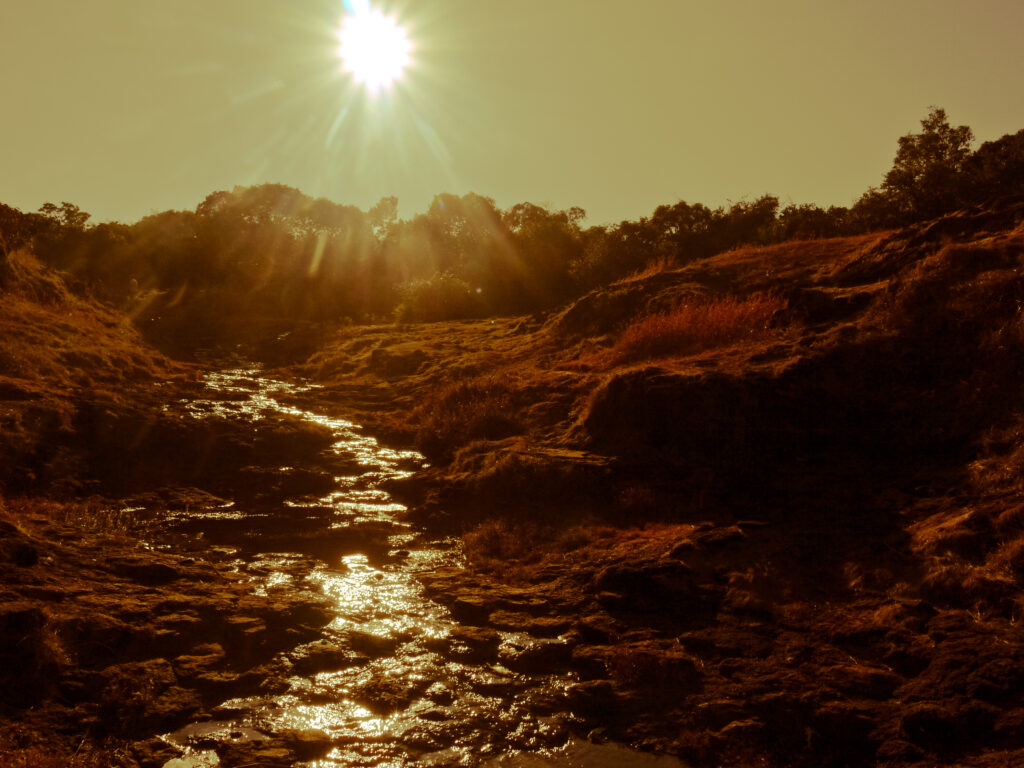 Serene river winding through rocky landscape at sunset with golden light and autumn foliage background Wallpaper