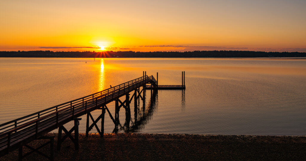 Wooden pier over calm river at golden sunset serene landscape perfect relaxing wallpaper background