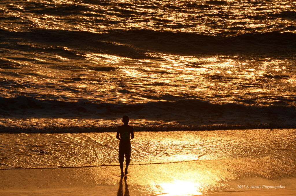 Silhouette on shore gazing at golden sunset waves peaceful sea reflective wallpaper background