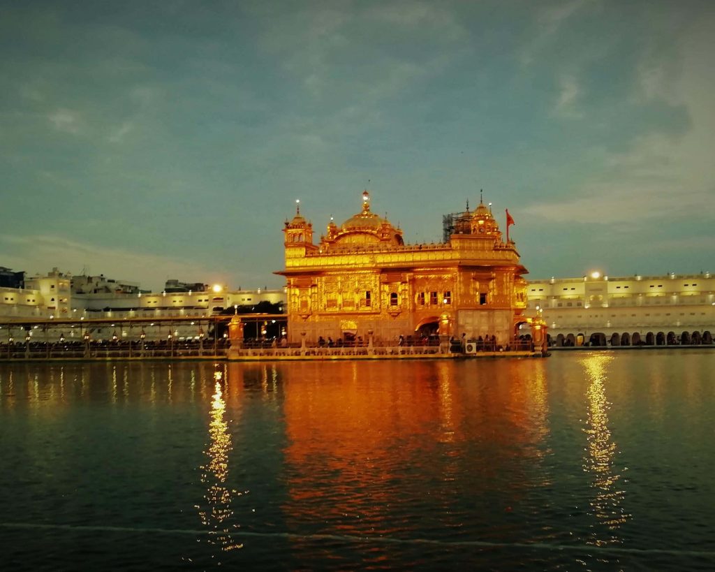 Golden Temple Amritsar illuminated at twilight reflecting in sacred water serene spiritual view Wallpaper