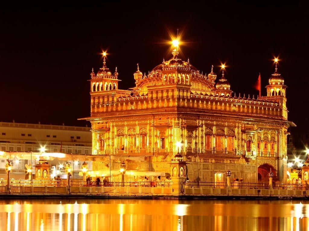 Golden Temple Amritsar at night glowing with gold reflection on calm Sarovar water peaceful scene Wallpaper