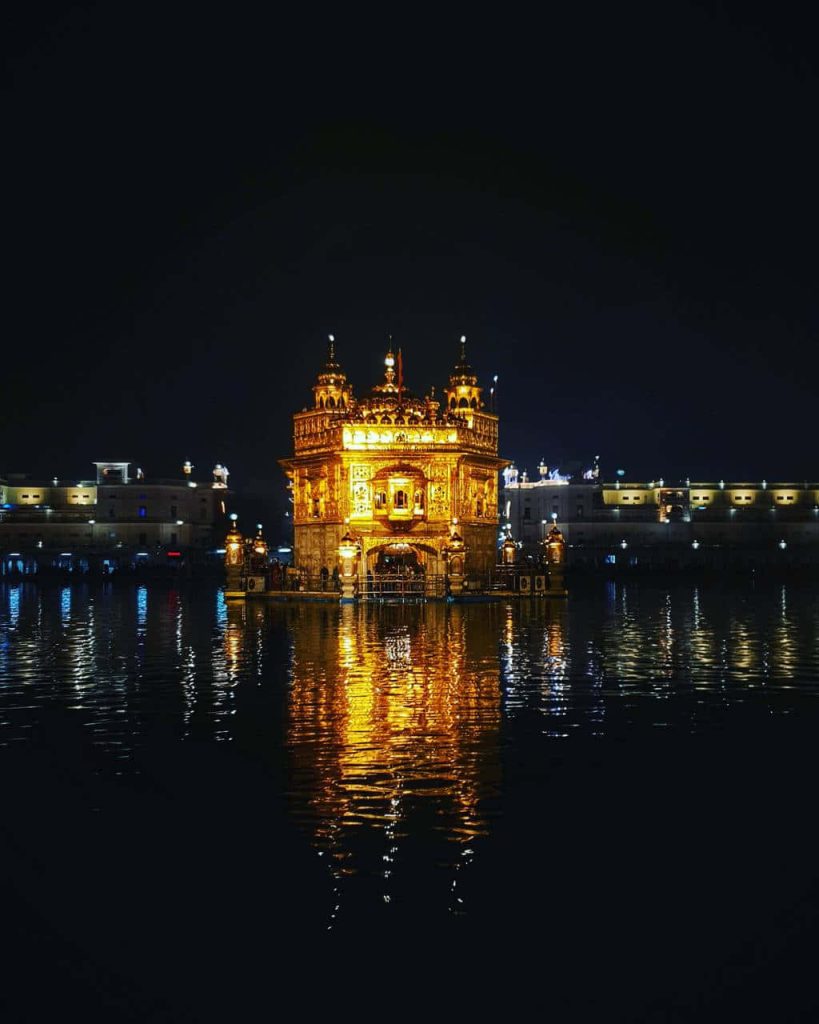 Golden Temple Amritsar illuminated at night reflecting on calm water serene spiritual view Wallpaper