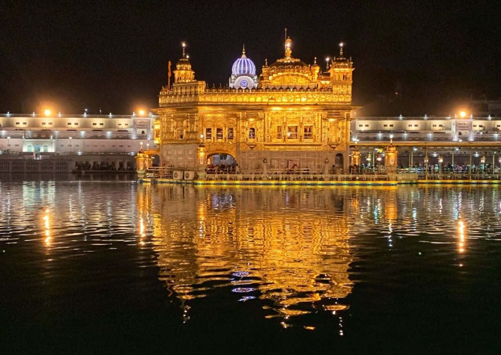 Golden Temple Amritsar night view illuminated reflection on calm Sarovar water serene twilight Wallpaper