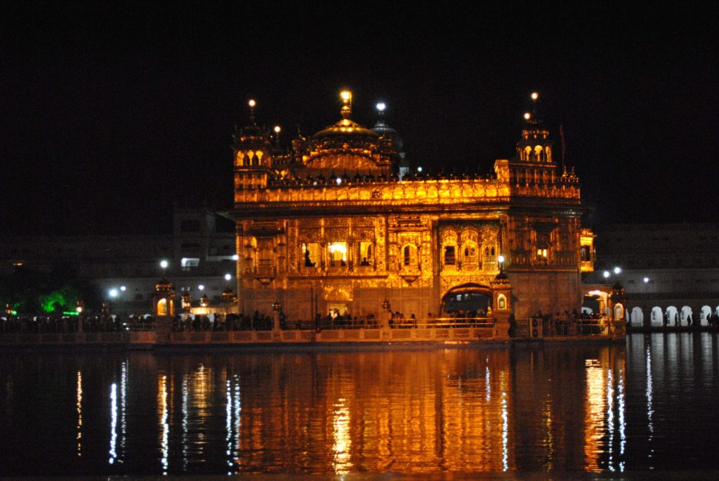 Golden Temple Amritsar glowing at night with golden reflection on Sarovar water serene wallpaper