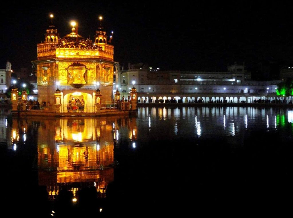 Golden Temple Amritsar illuminated at night reflecting on calm sacred pool serene spiritual scene Wallpaper