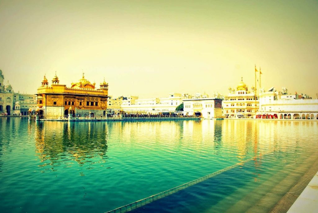 Golden Temple Amritsar glowing gold reflecting serene turquoise holy pool in warm sunlight Wallpaper