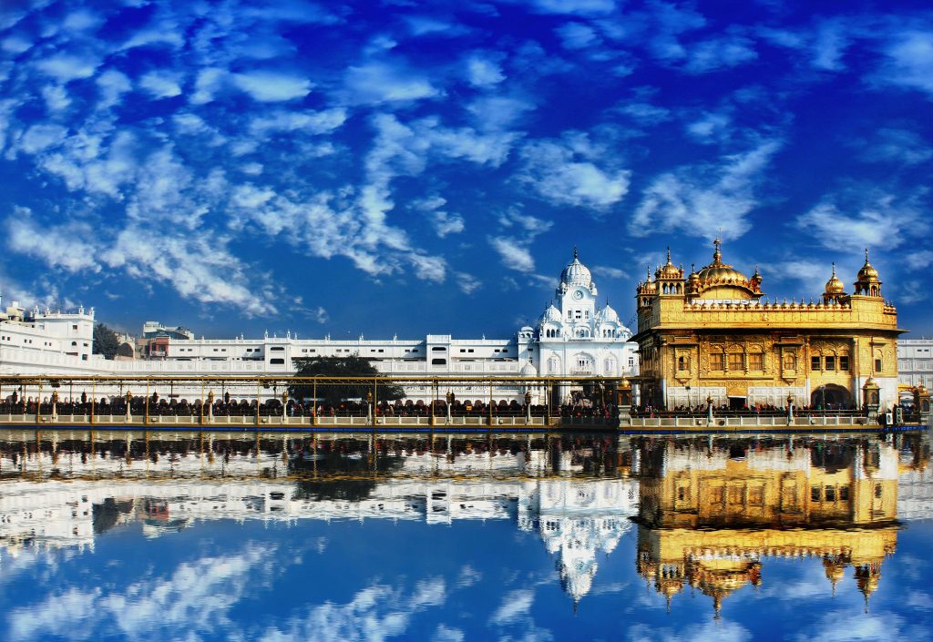 Golden Temple Amritsar glowing gold reflection in sacred pool under vibrant blue sky wallpaper