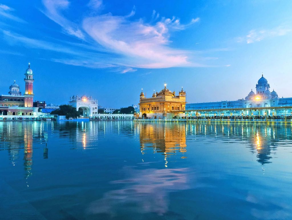 Golden Temple Amritsar glowing at twilight reflecting in calm holy pond serene spiritual landmark Wallpaper