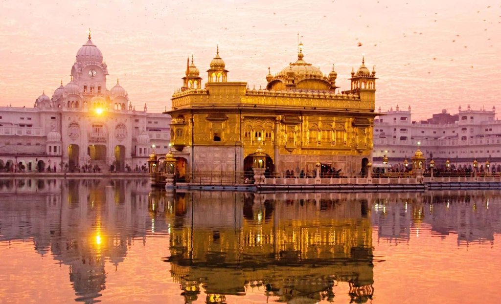 Golden Temple Amritsar glowing at golden hour with reflection in sacred pool at sunset Wallpaper