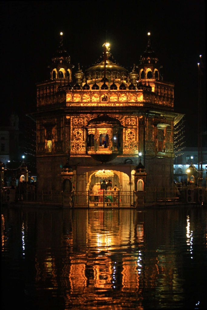 Golden Temple at night glowing with reflections on water serene spiritual landmark wallpaper