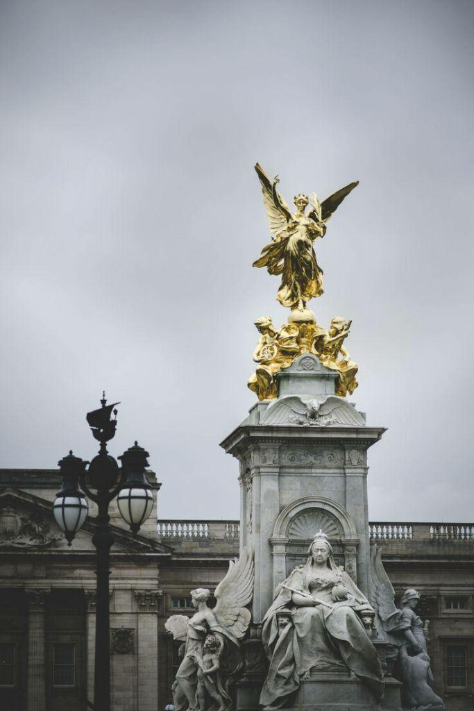 Golden sculpture atop Victoria Memorial Buckingham Palace with dramatic cloudy sky wallpaper background