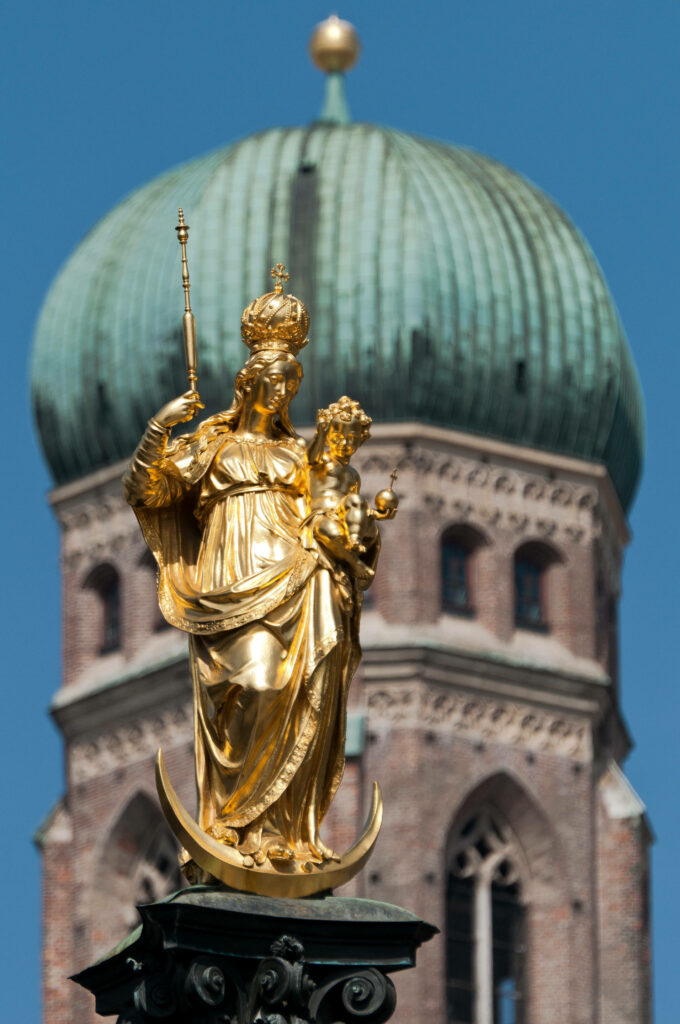 Golden Virgin Mary statue Munich with blurred Frauenkirche dome iconic city wallpaper background
