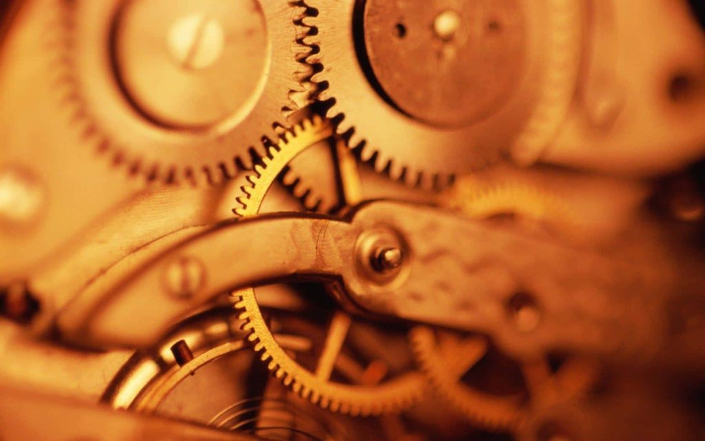 Macro close-up of golden watch movement gears in warm amber light showing intricate detail Wallpaper
