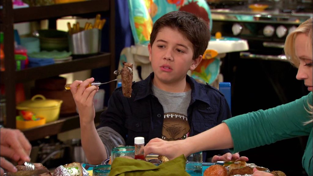 Gabe Duncan from Good Luck Charlie holding meat fork at family dinner in cozy kitchen Wallpaper