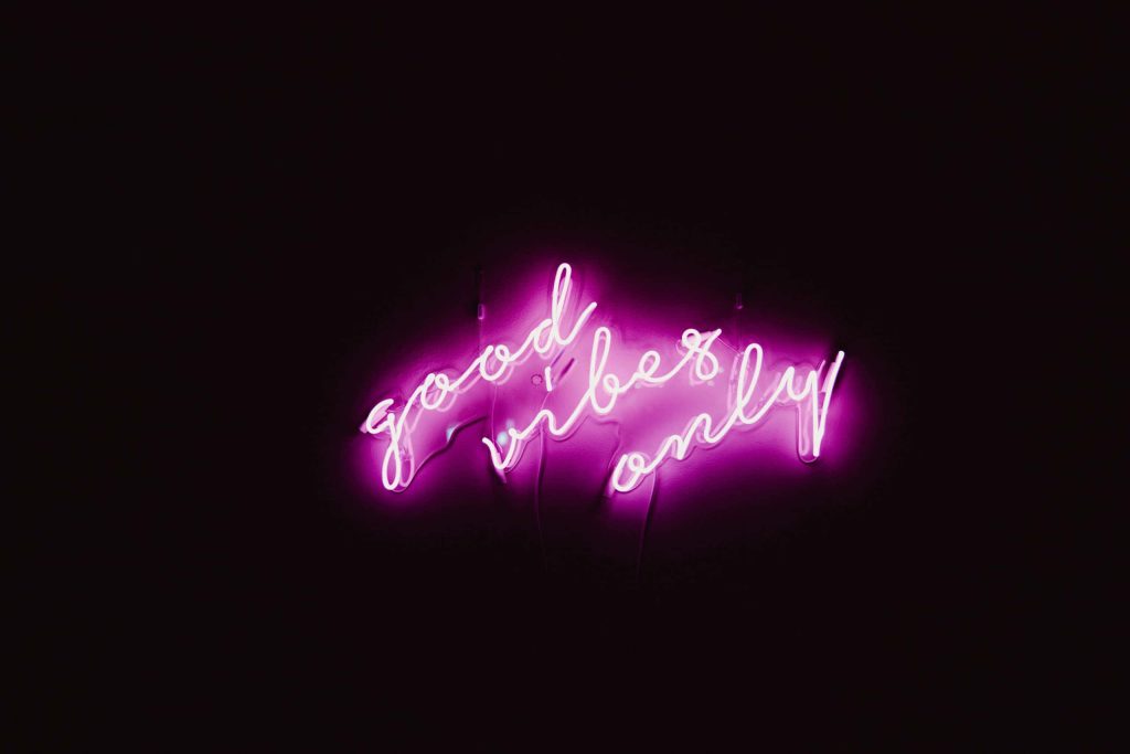 Vibrant pink neon good vibes only sign on sleek black background minimalist wallpaper design