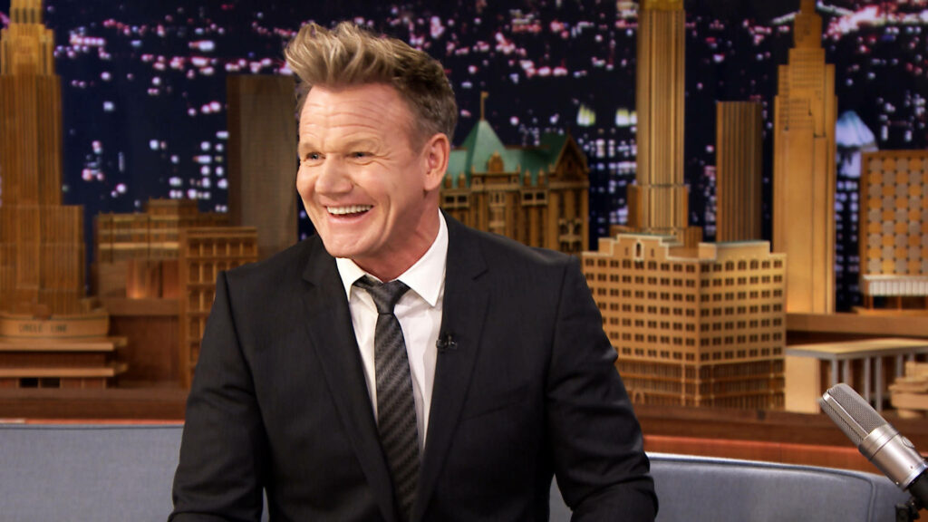 Gordon Ramsay Smiles in Suit on Tonight Show Set - Cityscape Wallpaper