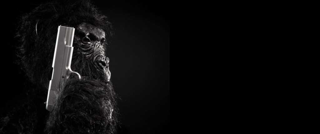 Gorilla with Silver Pistol Wallpaper: Dramatic Dark Background