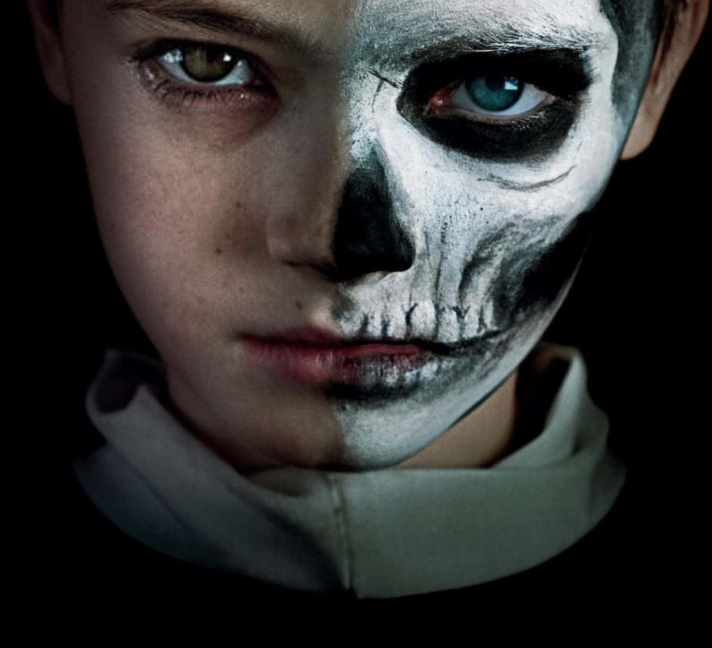 Young boy with black and white skeleton makeup split face gothic portrait on dark background wallpaper