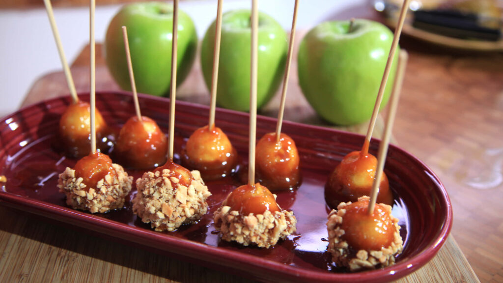Gourmet caramel apples with nuts on rustic wooden table warm autumn festive wallpaper background