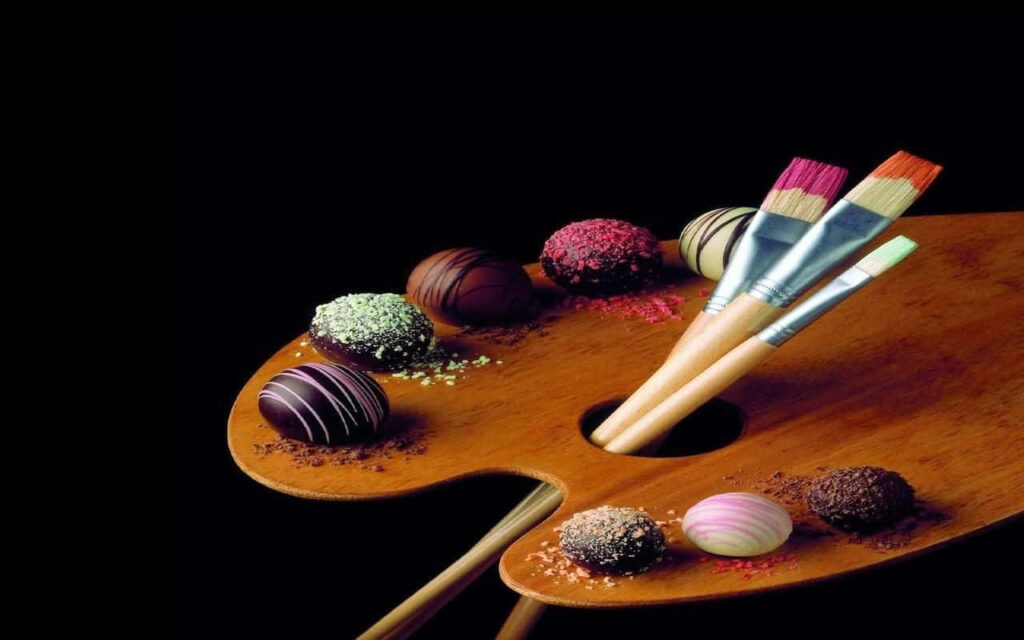 Artistic Wallpaper: Gourmet Chocolates & Paintbrushes on Dark Palette