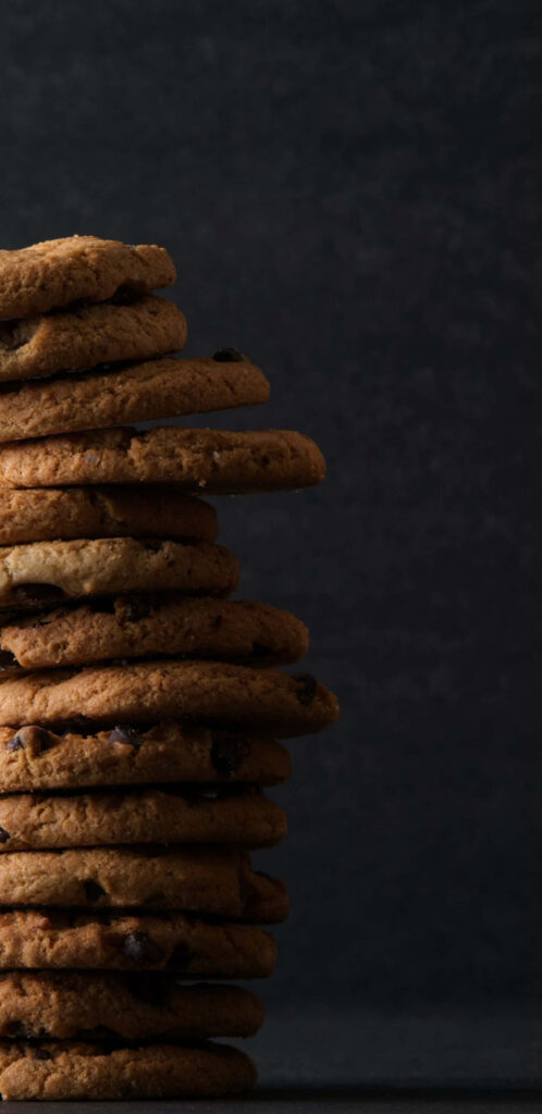 Stack of Chocolate Chip Cookies, adorning the Left Side against a Chic Gray Background Wallpaper