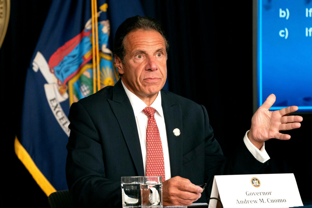 Governor Andrew Cuomo speaking at press conference with New York state flag and documents Wallpaper