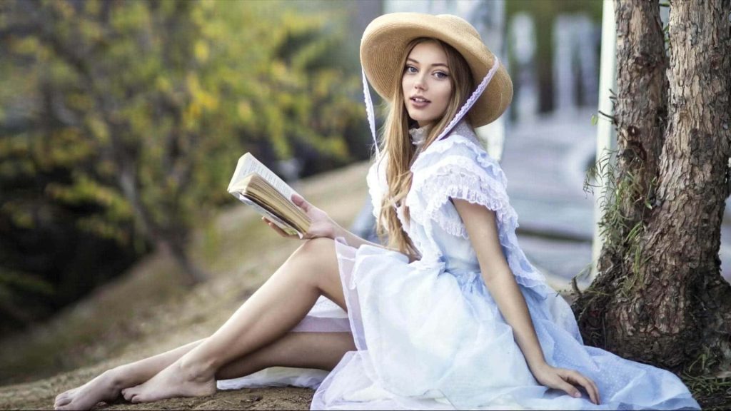 Grace Van Dien in vintage blue ruffled gown reading barefoot outdoors cozy cottagecore scene Wallpaper
