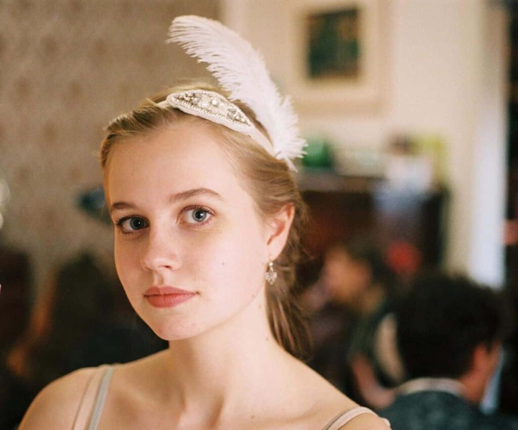 Graceful portrait of Angourie Rice in elegant feathered headpiece with soft vintage lighting wallpaper